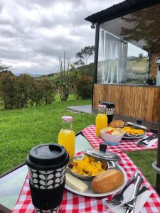 a picnic table with a plate of food and orange juice at ECO CABAÑAS EL ABUELO in La Calera