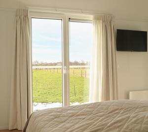 a bedroom with a large window with a view of a field at Wad & Loft unieke paalwoning vlakbij de Waddenzee in Pietersbierum