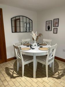 mesa de comedor blanca con sillas y espejo en The Old Bakery en South Cerney