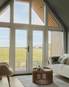 een woonkamer met een bank en een groot raam bij Wad & Loft unieke paalwoning vlakbij de Waddenzee in Pietersbierum