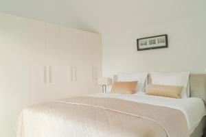 een witte slaapkamer met een groot wit bed met 2 kussens bij Wad & Loft unieke paalwoning vlakbij de Waddenzee in Pietersbierum