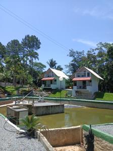 a house with a pond in front of a house at Chalé Girassol in Jaraguá do Sul