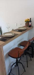 a wooden counter with two glasses and two stools at Chalé Girassol in Jaraguá do Sul