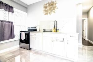 una cocina con armarios blancos y un aparato negro en Modern 1 Bedroom Apartment close Falls and Casino, en Niagara Falls