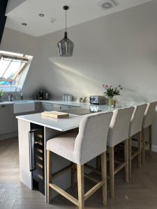 a kitchen with a large white island with bar chairs at Central Warwick, Free Parking and Roof Terrace in Warwick