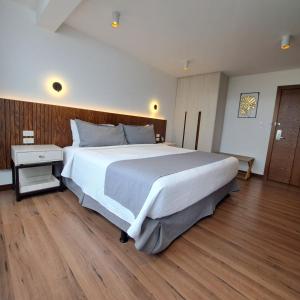 1 dormitorio con 1 cama blanca grande y suelo de madera en Hotel Ajavi, en Ibarra