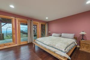 a bedroom with a bed and a large window at Blue Ridge Bliss Gorgeous home with hot tub & stunning views in Weaverville