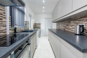 a kitchen with white cabinets and black counter tops at 2 Bedroom House in the Heart of Leicester in Leicester