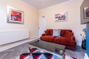 a living room with a red couch and a coffee table at 2 Bedroom House in the Heart of Leicester in Leicester
