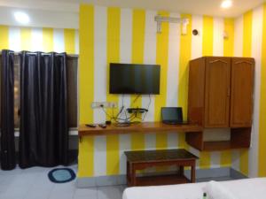 uma sala de estar com uma televisão numa parede listrada em amarelo e branco em HOTEL SOWMYA INN em Ongole