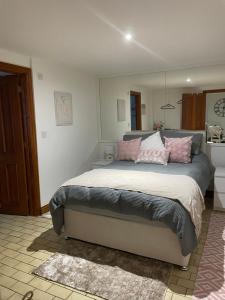 a bedroom with a large bed with pink pillows at The Old Bakery in South Cerney