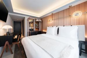 a bedroom with a large white bed and a desk at Muze Hotel in Düsseldorf