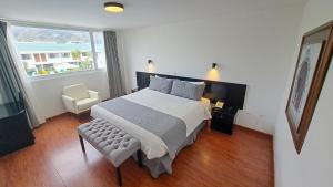 a bedroom with a bed and a chair and a window at Hotel Ajavi in Ibarra