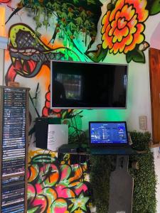 Elle comprend un bureau avec un ordinateur portable et un mur orné d'une peinture. dans l'établissement Chenille House HOSTAL con jardín y AC, à Munro