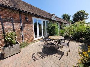 eine Terrasse mit einem Tisch und Stühlen sowie ein Backsteingebäude in der Unterkunft Little Ripple Cottage by Bloom Stays in Canterbury