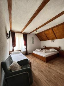 a bedroom with two beds and a couch in it at CONACUL DE SUB MUNTE in Novaci