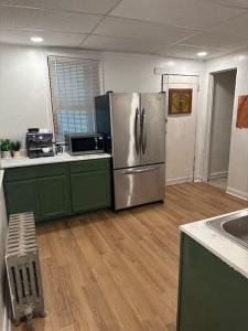 una cocina con nevera de acero inoxidable y armarios verdes en Comfy & Modern 3BR Home Free WiFi Free Parking, en Chicago