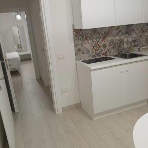 a kitchen with white cabinets and a tile floor at mya luxury rooms and wellness in Melendugno