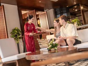 een groep van drie mensen die rond een tafel zitten bij Little Oasis - An Eco Friendly Hotel & Spa in Hội An