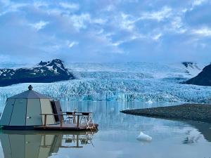 Fjallsarlon - Overnight adventure في هوف: وجود قارب جالس في الماء مع وجود نهر جليدي