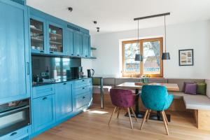 a kitchen with blue cabinets and a table and chairs at Hoixl Gütl auf der Fraueninsel in Frauenchiemsee