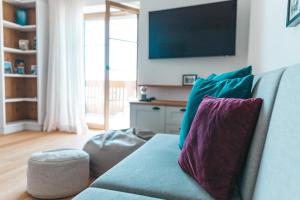 a living room with a couch with pillows and a tv at Hoixl Gütl auf der Fraueninsel in Frauenchiemsee