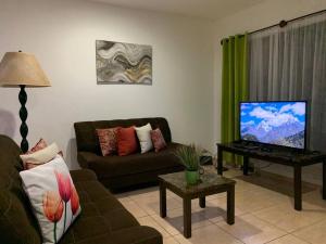 sala de estar con sofá y TV de pantalla plana en Casa Suiza – Schweizer Haus, en Liberia