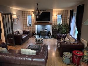 a living room with leather furniture and a fireplace at Awel Y Trydan in Llanon
