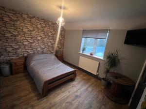 a bedroom with a bed and a stone wall at Awel Y Trydan in Llanon