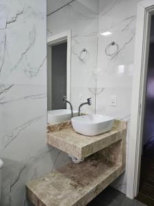 baño con lavabo blanco y paredes de mármol en POUSADA CITRINO, en Ametista do Sul 35 fotos más