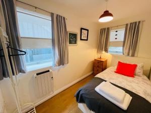 a bedroom with a bed with a red pillow on it at Our Happy Place- 2 bedroom apartment with designated parking - Brixham in Brixham