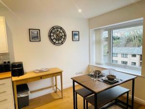 a kitchen with a table and a clock on the wall at Our Happy Place- 2 bedroom apartment with designated parking - Brixham in Brixham