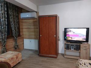 a living room with a television and a wooden cabinet at Студио Тони in Burgas