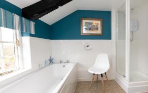 a bathroom with a white tub and a chair in it at The Old Farmhouse in Liskeard