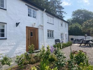 a white building with a wooden door in a garden at The Old Farmhouse in Liskeard