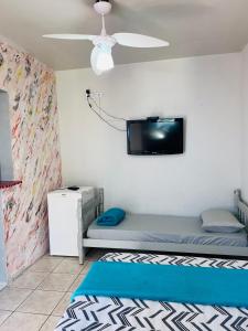 a bedroom with a bed and a tv on the wall at Pousada Villa Brasil Ocian in Praia Grande