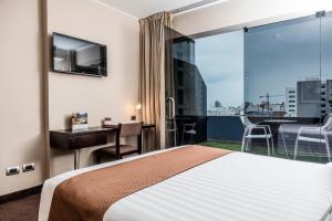 a hotel room with a bed and a desk and a balcony at Del Pilar Miraflores Hotel in Lima