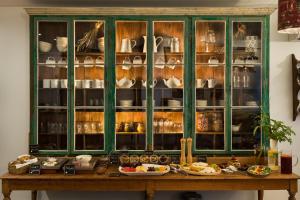 a green china cabinet with dishes in it at Altanure - Almatere Food Forest Boutique Hotel in Tavira