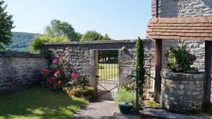 a garden with a stone wall with a gate and flowers at L'Ancienne Cure in Besain