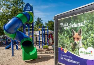 a playground with a slide in front of a sign at Huisje in Stijl in Ermelo