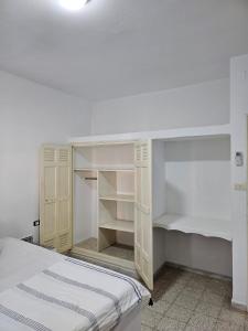 a white bedroom with a bed and white shelves at App 2 chambres rdc 200m de la plage in Mezraya