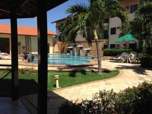 a swimming pool in a resort with a palm tree at Vilamar Suítes in Aquiraz
