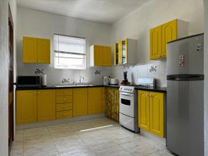 a kitchen with yellow cabinets and a refrigerator at Lailamar Villa, Ocean view & Pool - Ground Floor in Saint Philip