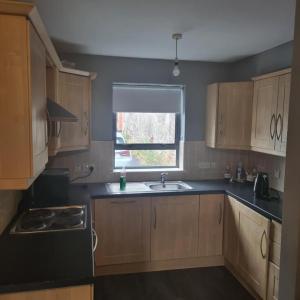 d'une cuisine avec des placards en bois, un évier et une fenêtre. dans l'établissement LARGE 3 BEDROOM HOME, 3 BATHROOMS, FREE PARKING, FAST WIFI, à Belfast