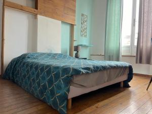 a bed with a blue comforter in a bedroom at Maison 5 chambres proche toutes commodités in Roubaix