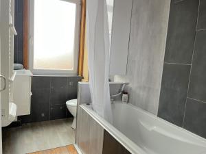 a bathroom with a tub and a toilet and a window at Maison 5 chambres proche toutes commodités in Roubaix