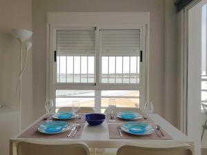 a table with plates and glasses and a window at Valdelagrana Mar Ha Apartment in El Puerto de Santa María