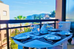 niebieski stół z talerzami i kieliszkami do wina na balkonie w obiekcie Somptueux deux pieces, entre mer & piscine ! w mieście Mandelieu-la-Napoule