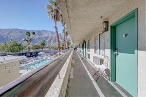 a balcony with a door and a chair next to a pool at The Infusion Beach Club in Palm Springs