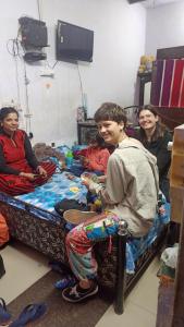 een groep mensen die rond een bed zitten bij Shiva guest House (hoche poche cafe ) in Agra